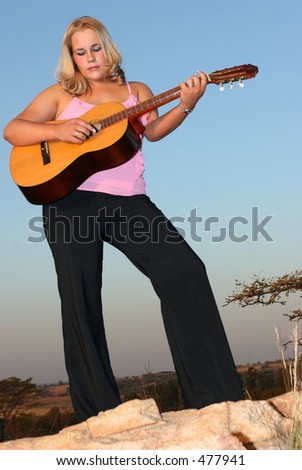 Woman standing and playing music on a guitar