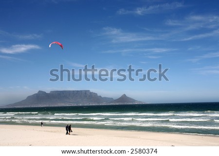 A landscape of ocean and sea with people walking on beach