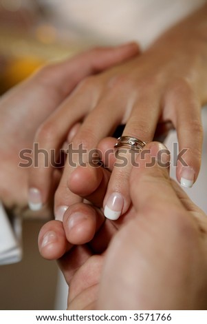 A groom putting a ring on his brides finger