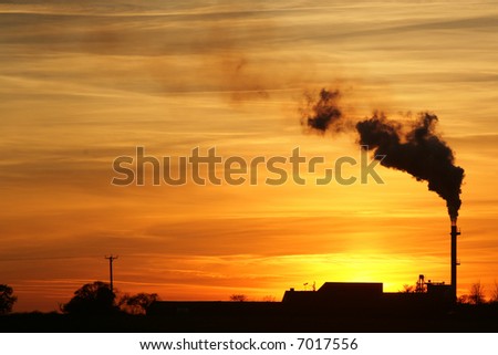 A beautiful sunset behind a factory with a smoking chimney