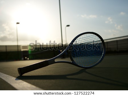 Tennis Racket on the Court backlit by the Setting Sun