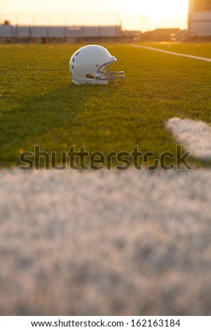 American Football Helmet Backlit on the Field at Sunset with room for copy