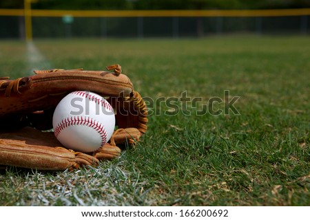 New Baseball in a Glove in the Outfield with room for copy