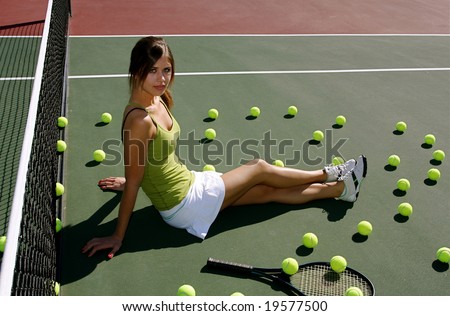 Brunette woman on the tennis court surrounded by tennis balls