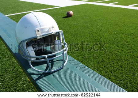 American Football Helmet on the Bench with ball and field in the background