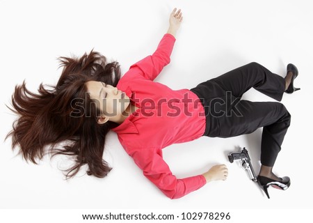 Office lady lying on ground with gun, looks like crime scene.