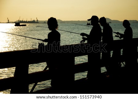 Fishing man silhouette on bridge with sea background, Thailand