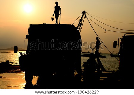 Silhouette of man on truck with sunset sky, Worker breaking the ice for fishing boat