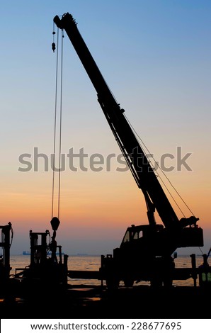 Silhouette crane working at port with sunset sky background