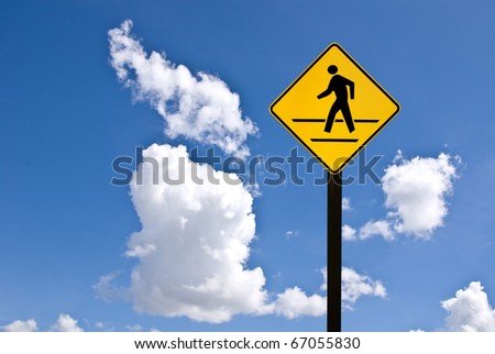 A yellow man walking sign with blue sky