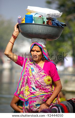 UDAIPUR, INDIA - JAN. 25: Unidentified Indian woman carries supplies to wash clothes in the Udaipur lake on January 25, 2011 in Udaipur. Washing clothes in public is common in India.