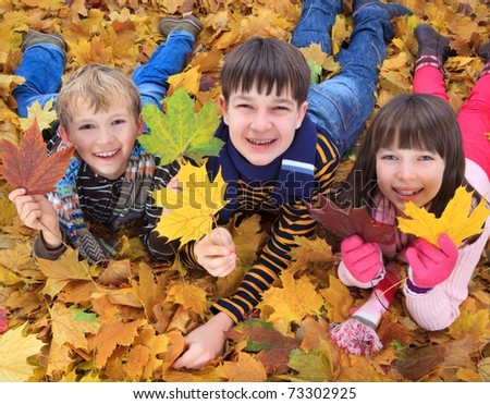 Brothers and sister playing outside in Autumn leaves.