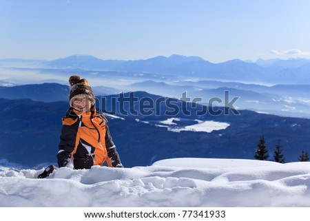 Portrait of happy young boy playing with snow on Alpine mountain summit.