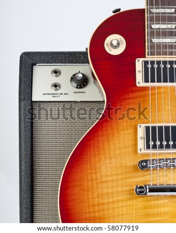 Sunburst electric guitar standing up against a vintage amp with inputs and knob showing