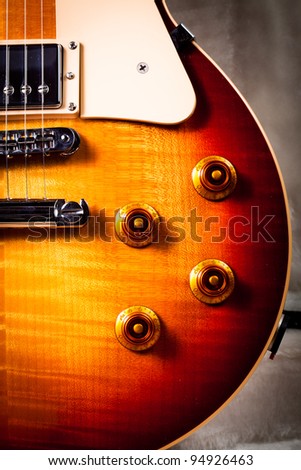 Close Up of the Corner of a Sunburst Electric Guitar with the Knobs, Pick Guard and Pickups