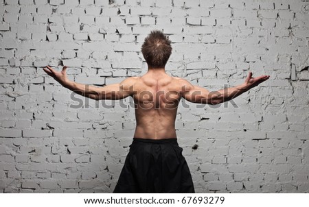Strong muscular man back at  white wall background in flying and free standing