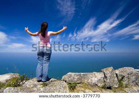 young woman with arms wide open contemplating the ocean