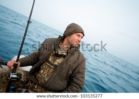 Angler fisherman catches a salmon trolling in the sea.