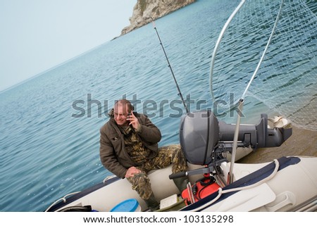 Fisherman was talking on his mobile phone after fishing in the sea.