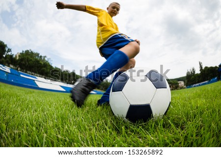 Boy soccer player hits the ball on the football field. Fish-eye lens.