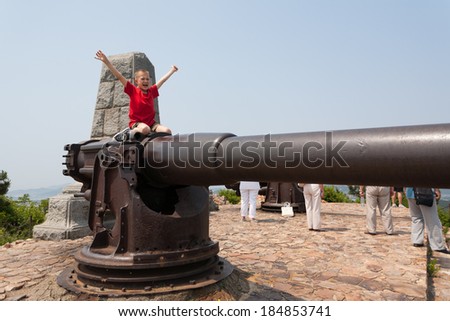 Boy on a gun in the old Russian fort in Lyushyun (Russian name Port Arthur). East China.