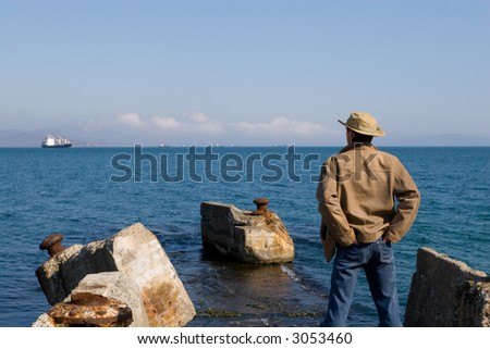 The young man stands on ruins of an old sea pier.Spring.