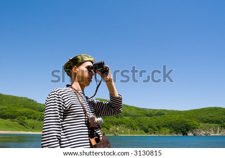 The young man looks in the old binocular.On a neck the old camera hangs.