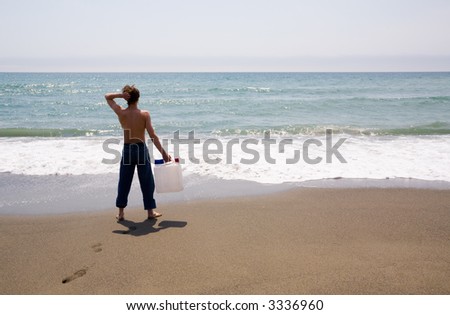 The young man stands at the sea and holds in a hand the empty canister for water.Fun.