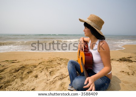 The girl holds a guitar and looks at the sea.