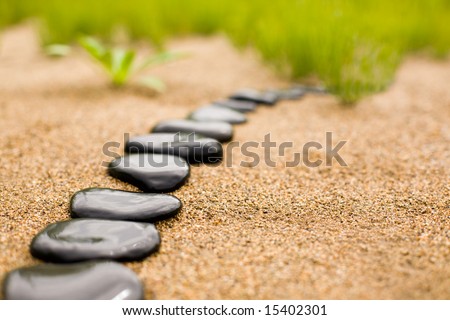 Abstract stone path on sand on a background of a grass