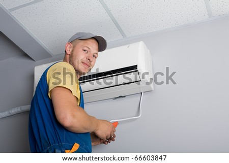 Young setup man installs the new air conditioner in the office.