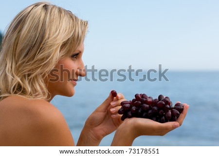 Beautiful girl eating grapes against the sea