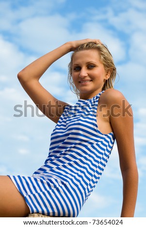 Attractive young woman in sailor\'s striped vest against the sky. Evening.