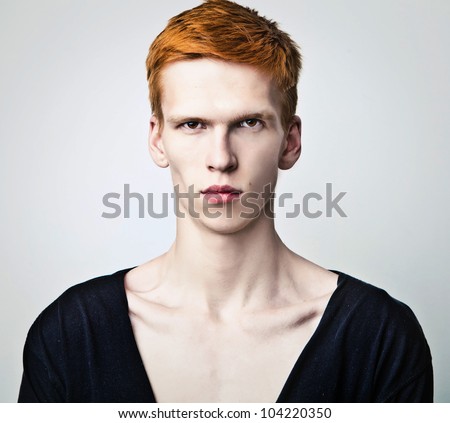 Young red haired man on light background.