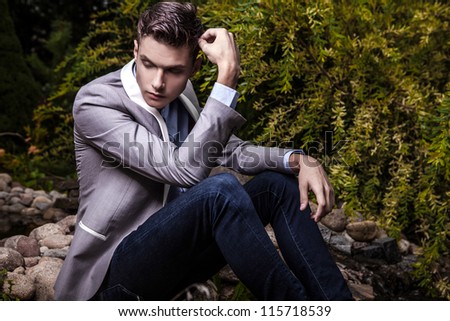 Portrait of young beautiful fashionable man against autumn garden.