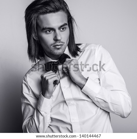 Portrait of handsome long-haired stylish man with bow tie. Black-white photo.