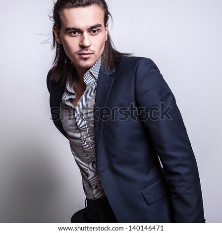 Elegant young handsome long-haired man in costume. Studio fashion portrait.