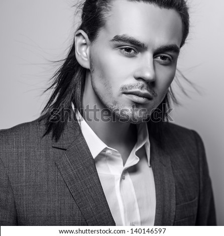 Elegant young handsome long-haired man in costume. Black-white fashion portrait.