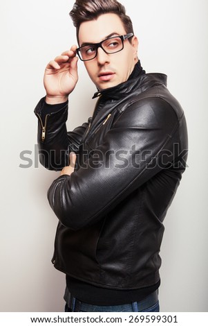 Elegant young handsome man in black leather jacket and stylish glasses.