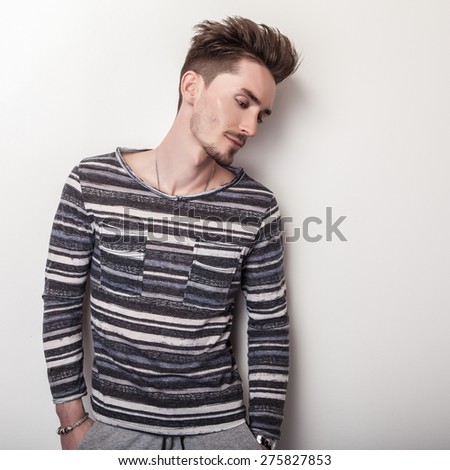 Elegant young handsome man in bright striped gray t-shirt. Studio fashion portrait.