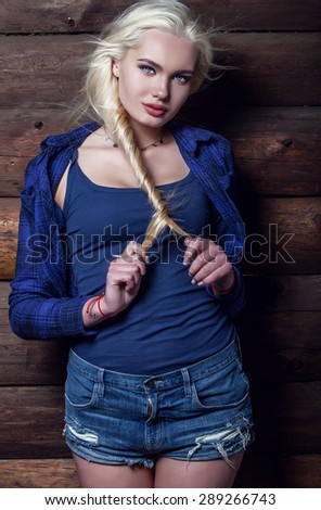 Attractive young blond beauty woman in blue casual shirt pose against wooden background.