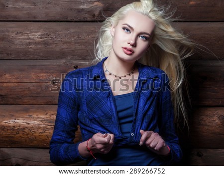 Attractive young blond beauty woman in blue casual shirt pose against wooden background.