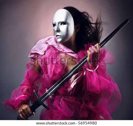 Woman warrior in a silver mask with a sword in hands. Photo.