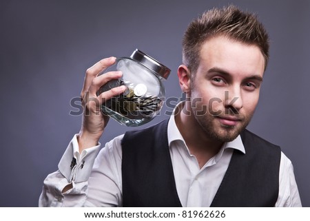 Young business man holding jar with coins  - retirement fund and savings concept