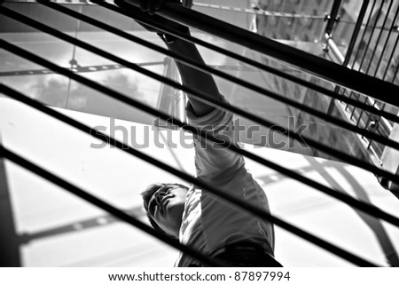 Young businessman standing in bright office balcony. Black-white photo.