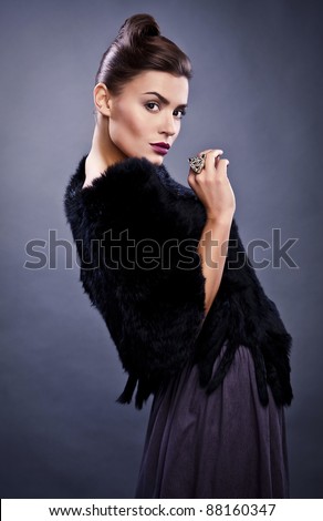 Close-up face portrait of stylish&fashionable pretty woman in fur against grey background.