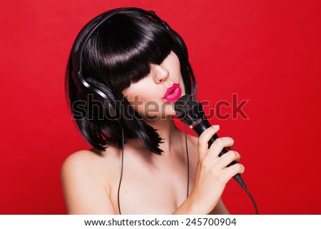 Woman listening to music on headphones enjoying a singing. Closeup portrait of beautiful girl with pink lips