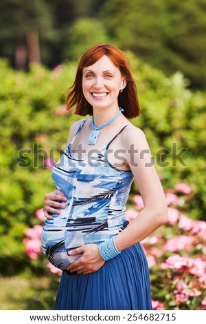 Outdoor natural portrait of beautiful smiling pregnant woman