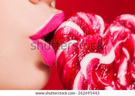 Closeup photo of a beautiful sexy red lips with lollipop