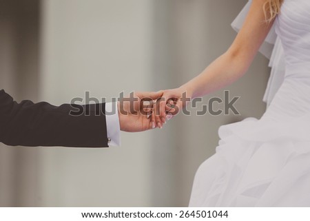 Bride and groom holding hands outdoors. Wedding theme, holding hands newlyweds